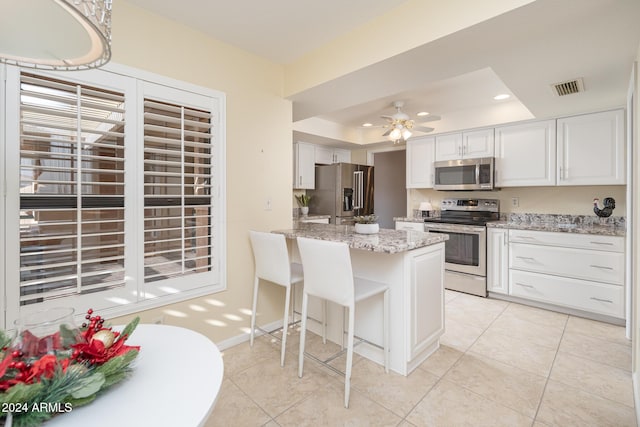 kitchen with a breakfast bar, white cabinets, ceiling fan, kitchen peninsula, and stainless steel appliances