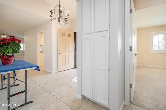 corridor with light tile patterned floors and a notable chandelier