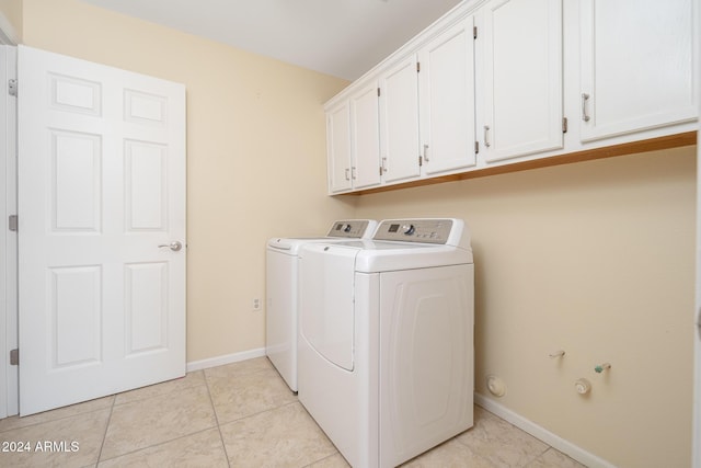 laundry room with washing machine and dryer, light tile patterned floors, and cabinets