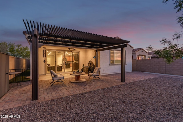 11658 E Chevelon Trl, Gold Canyon, AZ 85118 - back of property at dusk with stucco siding, a patio, a fenced backyard, ceiling fan, and a fire pit