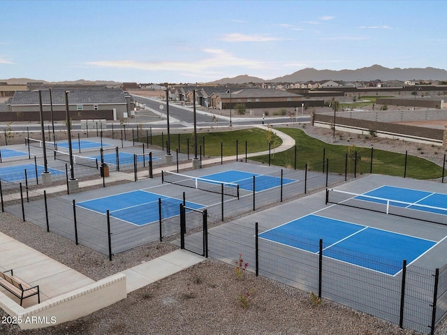 view of tennis court featuring a residential view, a mountain view, and fence