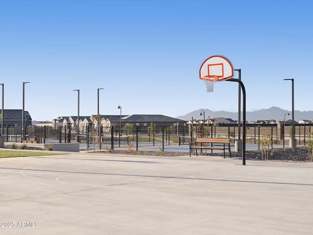 view of sport court with a mountain view, community basketball court, and fence