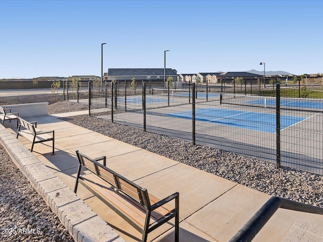 view of tennis court with a residential view and fence