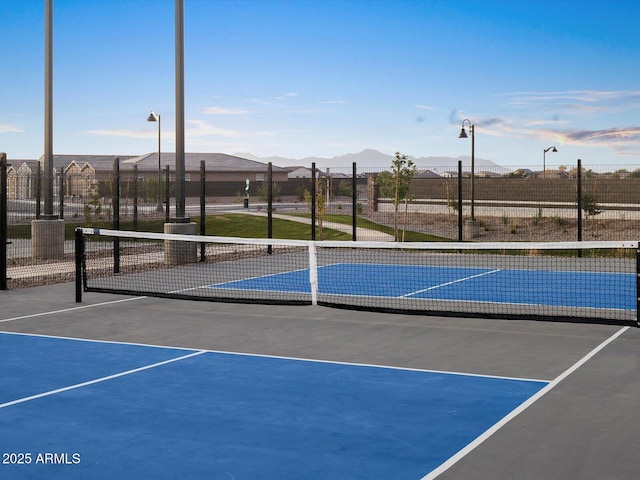 view of tennis court featuring fence and a mountain view