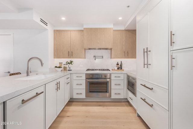 kitchen featuring appliances with stainless steel finishes, sink, light brown cabinetry, and light hardwood / wood-style floors