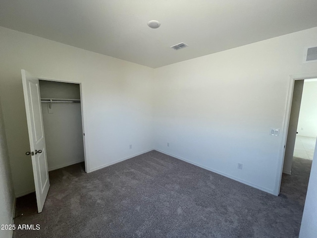 unfurnished bedroom with dark colored carpet and a closet