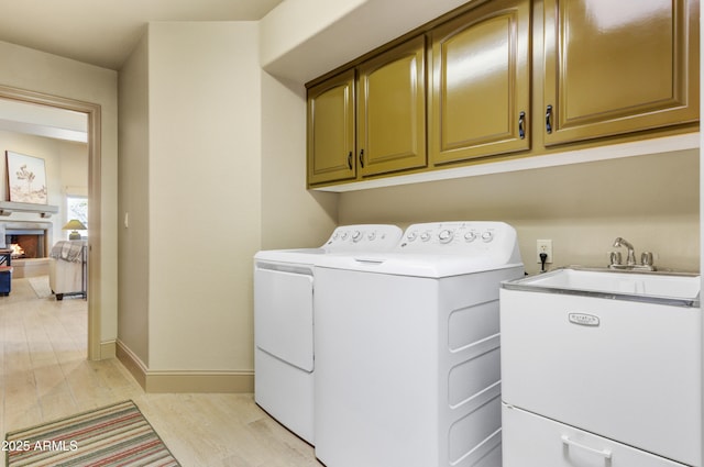 laundry room featuring cabinets, light wood-type flooring, and washer and clothes dryer