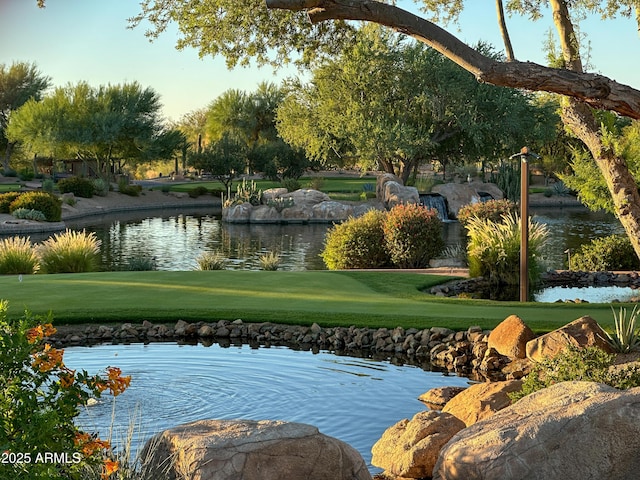 view of home's community with a water view and a yard