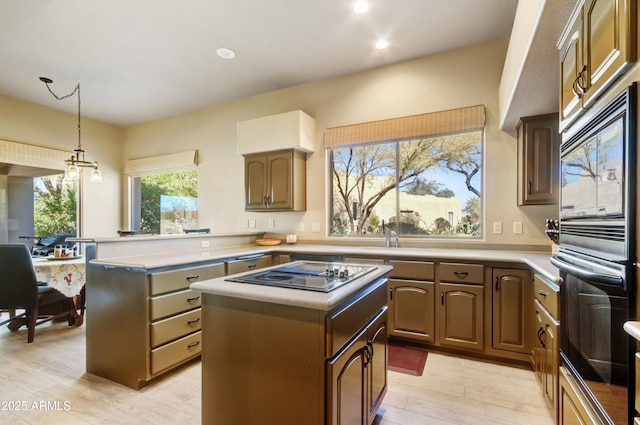 kitchen featuring pendant lighting, stainless steel gas stovetop, a center island, sink, and built in microwave