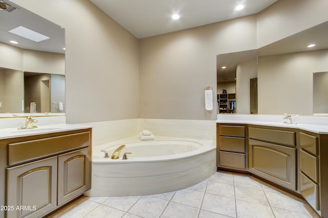 bathroom featuring tile patterned flooring, a bathtub, vanity, and a skylight