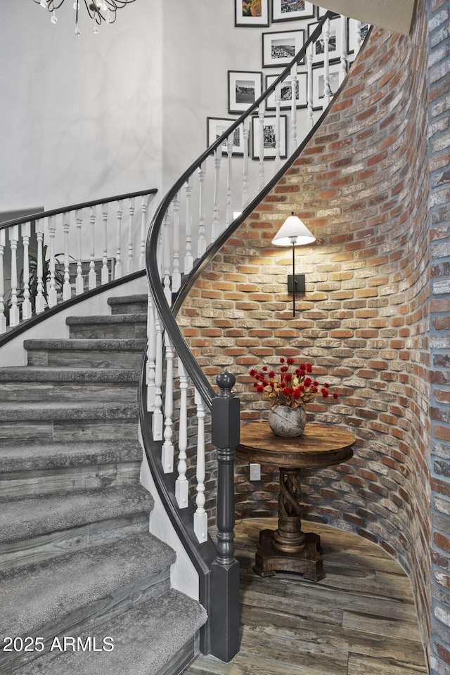 3770 E Ringtail Way, Phoenix, AZ 85050 - stairs featuring wood finished floors, a towering ceiling, brick wall, and a chandelier