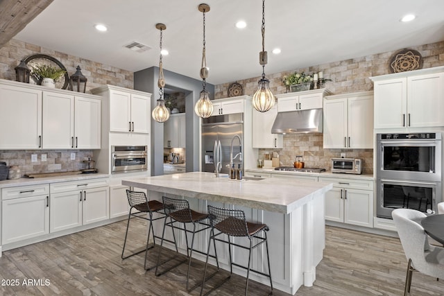 3770 E Ringtail Way, Phoenix, AZ 85050 - kitchen featuring stainless steel appliances, under cabinet range hood, tasteful backsplash, a breakfast bar area, and recessed lighting