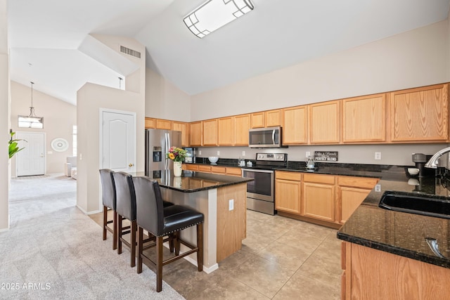 3488 N Lady Lake Ln, Casa Grande, AZ 85122 - kitchen with stainless steel appliances, a sink, high vaulted ceiling, light brown cabinetry, and dark stone countertops