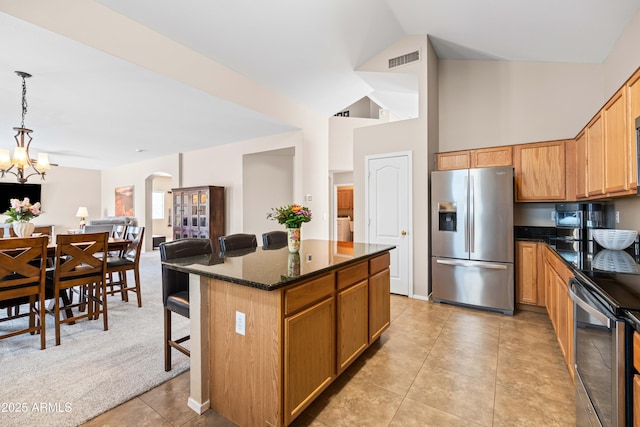 3488 N Lady Lake Ln, Casa Grande, AZ 85122 - kitchen featuring stainless steel appliances, a center island, arched walkways, dark stone counters, and decorative light fixtures