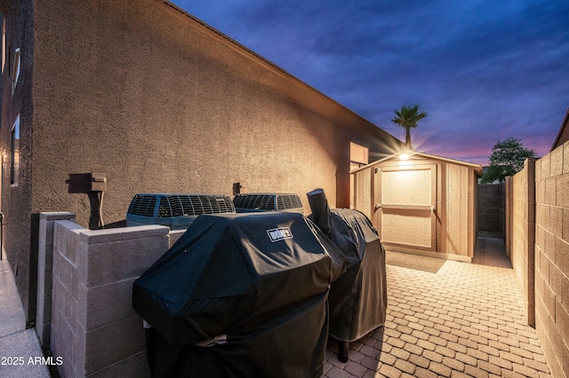 3488 N Lady Lake Ln, Casa Grande, AZ 85122 - property exterior at dusk featuring a shed, an outdoor structure, stucco siding, and a fenced backyard