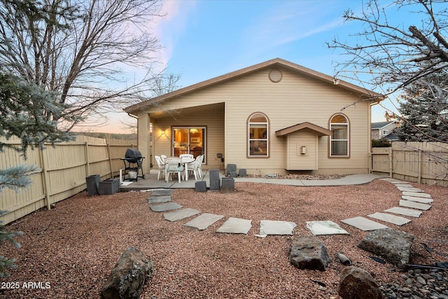 back house at dusk featuring a patio