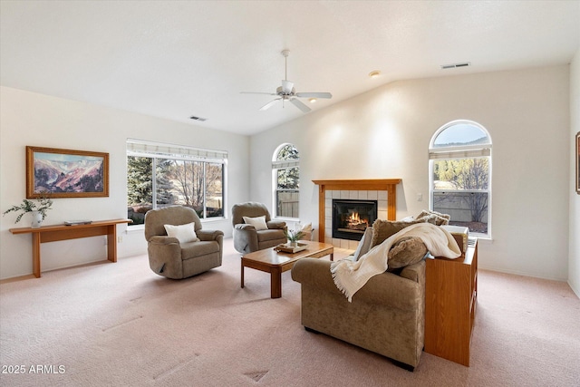 living room with ceiling fan, lofted ceiling, light carpet, and a tiled fireplace