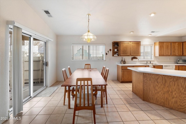 tiled dining area featuring sink, lofted ceiling, and an inviting chandelier