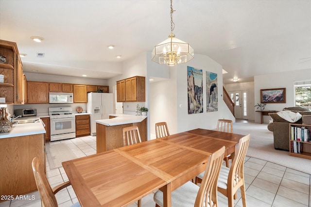 dining area with a notable chandelier, light tile patterned floors, sink, and lofted ceiling