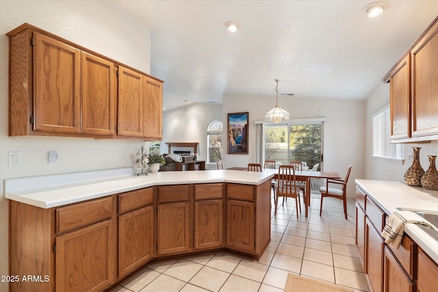 kitchen with kitchen peninsula, pendant lighting, light tile patterned floors, and lofted ceiling