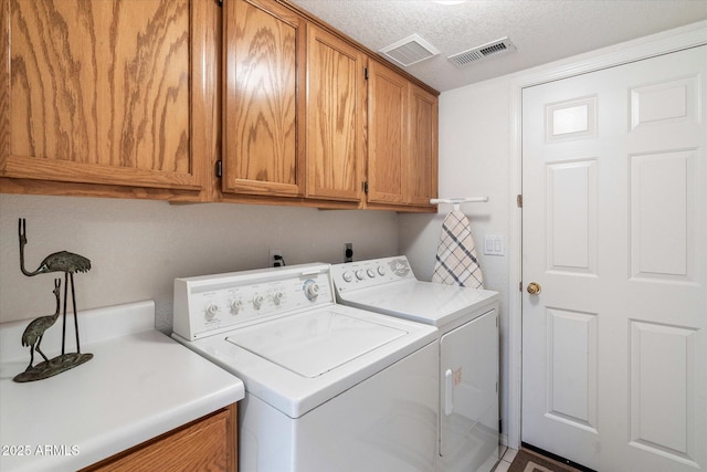 laundry area with washer and dryer, cabinets, and a textured ceiling