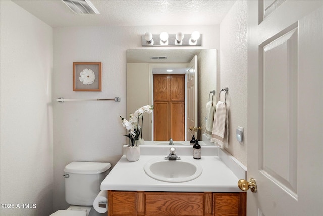 bathroom featuring a textured ceiling, vanity, and toilet