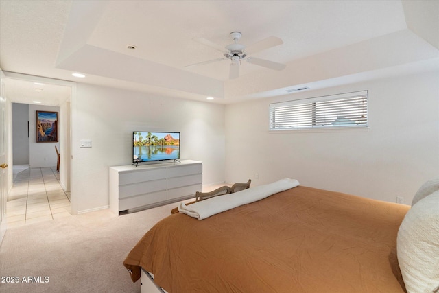 carpeted bedroom featuring a raised ceiling and ceiling fan