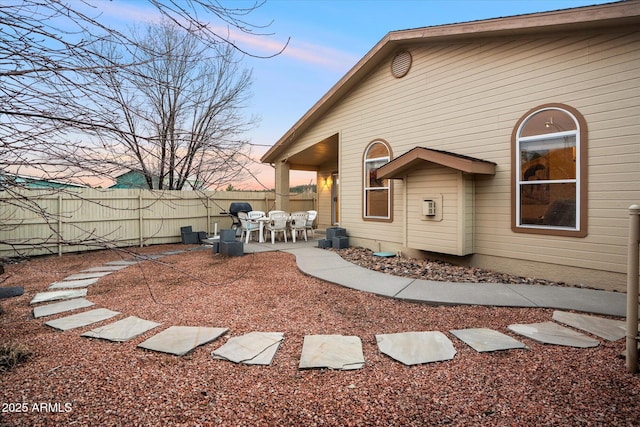 back house at dusk featuring a patio area