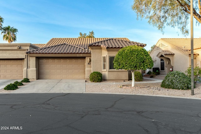 view of front of home featuring driveway, a tiled roof, an attached garage, and stucco siding