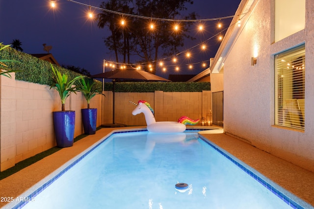 pool at night featuring a jacuzzi