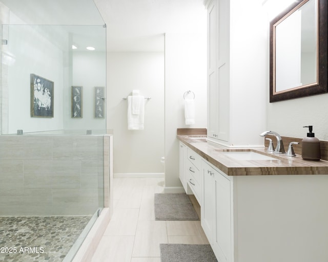 bathroom with tile patterned floors, tiled shower, and vanity