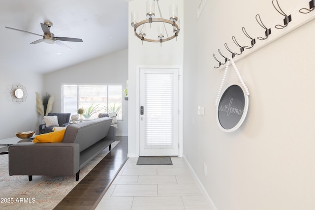 foyer featuring lofted ceiling, ceiling fan with notable chandelier, and light tile patterned floors