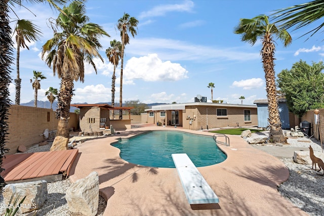 view of swimming pool featuring an outbuilding, a storage structure, a fenced backyard, and a diving board