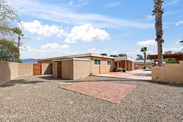 rear view of property with a swimming pool, a patio, and fence