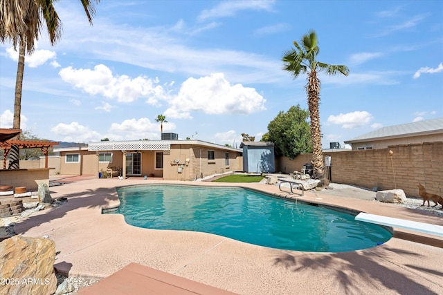 view of swimming pool with a fenced in pool, a patio, fence private yard, and a shed