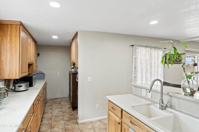 kitchen with a sink, light tile patterned flooring, recessed lighting, and light countertops