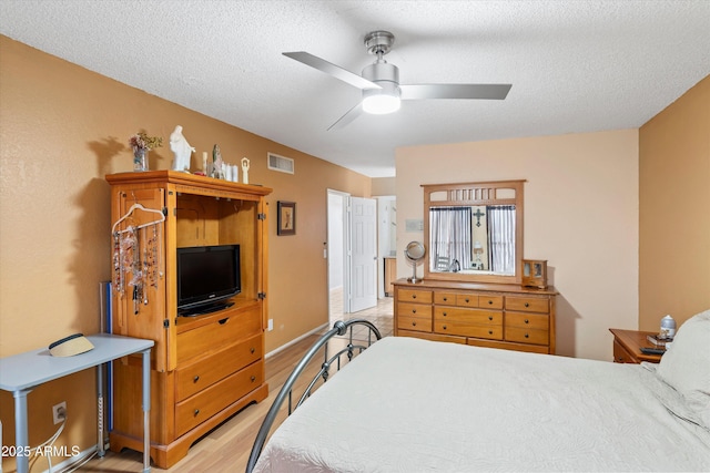 bedroom with light wood-style flooring, baseboards, visible vents, and a textured ceiling