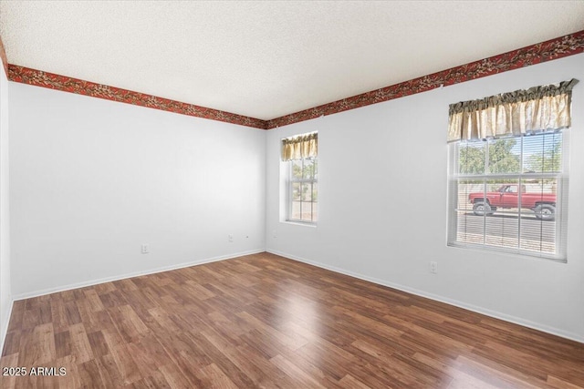 empty room featuring baseboards, a textured ceiling, and wood finished floors