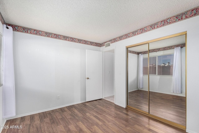 unfurnished bedroom featuring a textured ceiling, visible vents, and wood finished floors