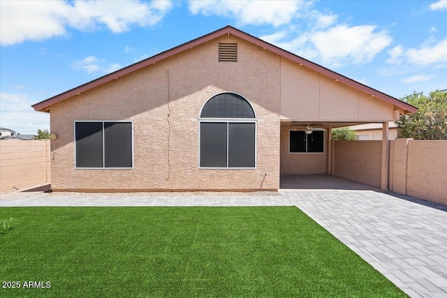 back of house featuring a lawn, a patio area, fence, and stucco siding