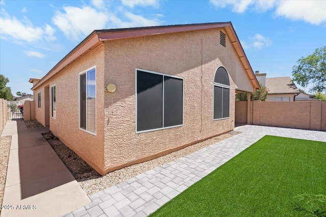 view of home's exterior with a lawn, stucco siding, a fenced backyard, and a patio area