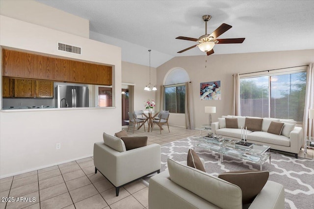 living room featuring light tile patterned floors, a wealth of natural light, vaulted ceiling, and visible vents