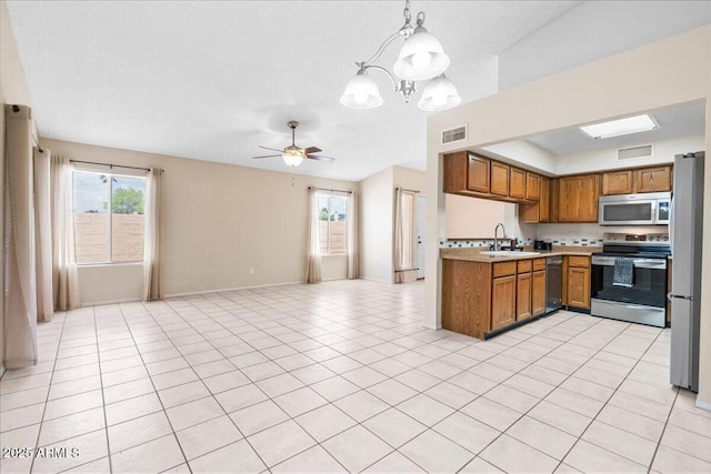 kitchen with brown cabinets, light countertops, stainless steel appliances, open floor plan, and visible vents