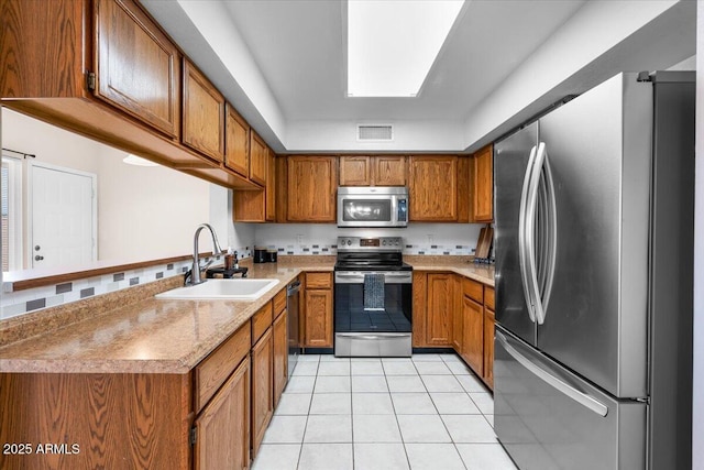 kitchen featuring a sink, stainless steel appliances, brown cabinets, and visible vents
