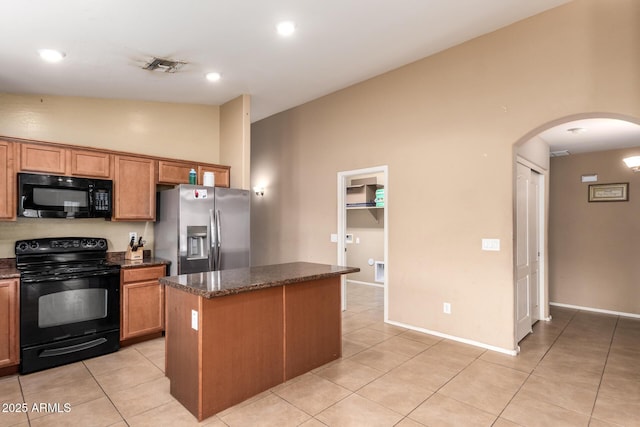 23613 W Mobile Ln, Buckeye, AZ 85326 - kitchen with black appliances, arched walkways, a center island, light tile patterned floors, and lofted ceiling