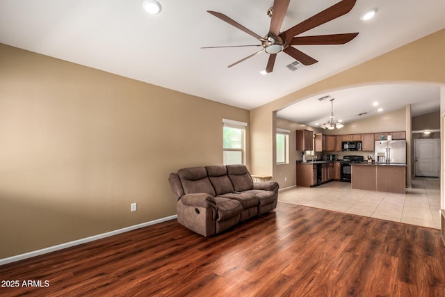 23613 W Mobile Ln, Buckeye, AZ 85326 - living area with vaulted ceiling, arched walkways, a ceiling fan, a chandelier, and light wood-style flooring
