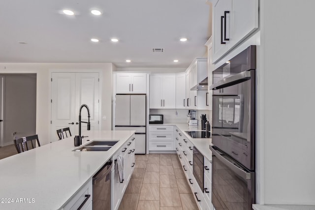 kitchen with sink, multiple ovens, stainless steel dishwasher, white fridge, and white cabinetry