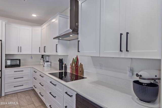 kitchen featuring light stone countertops, white cabinetry, wall chimney range hood, light tile patterned floors, and black appliances