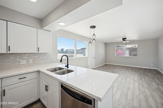 kitchen featuring a peninsula, a sink, white cabinetry, light countertops, and stainless steel dishwasher