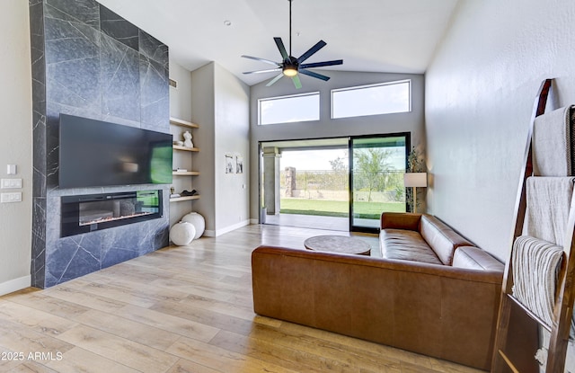 living area featuring built in shelves, wood finished floors, a high end fireplace, and baseboards